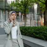 Confident woman in hijab making a call outside an office building.