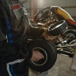 Mechanic working on a kart tire in an indoor garage setting, showcasing racing preparation.