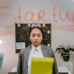 A young professional woman standing in a startup office with creative elements.