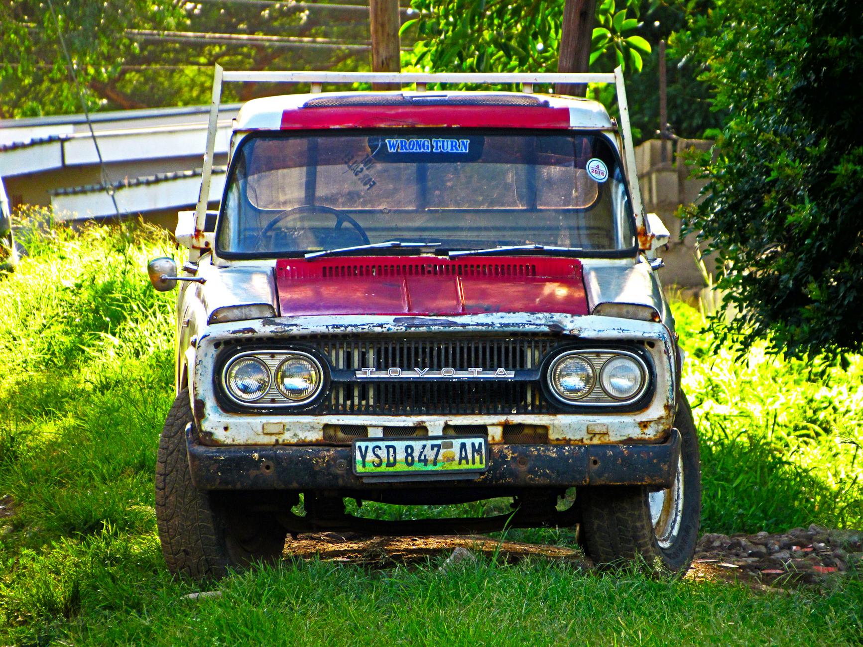 Rusted vintage Toyota truck parked in grassy field, Manzini, Eswatini.