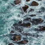 Powerful ocean waves crashing against rocks, capturing the force of the sea.