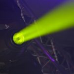 Close-up of a vivid neon spotlight emitting a green beam, part of modern stage lighting equipment.