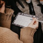 A woman writing on a paper playing a word game during a social gathering.