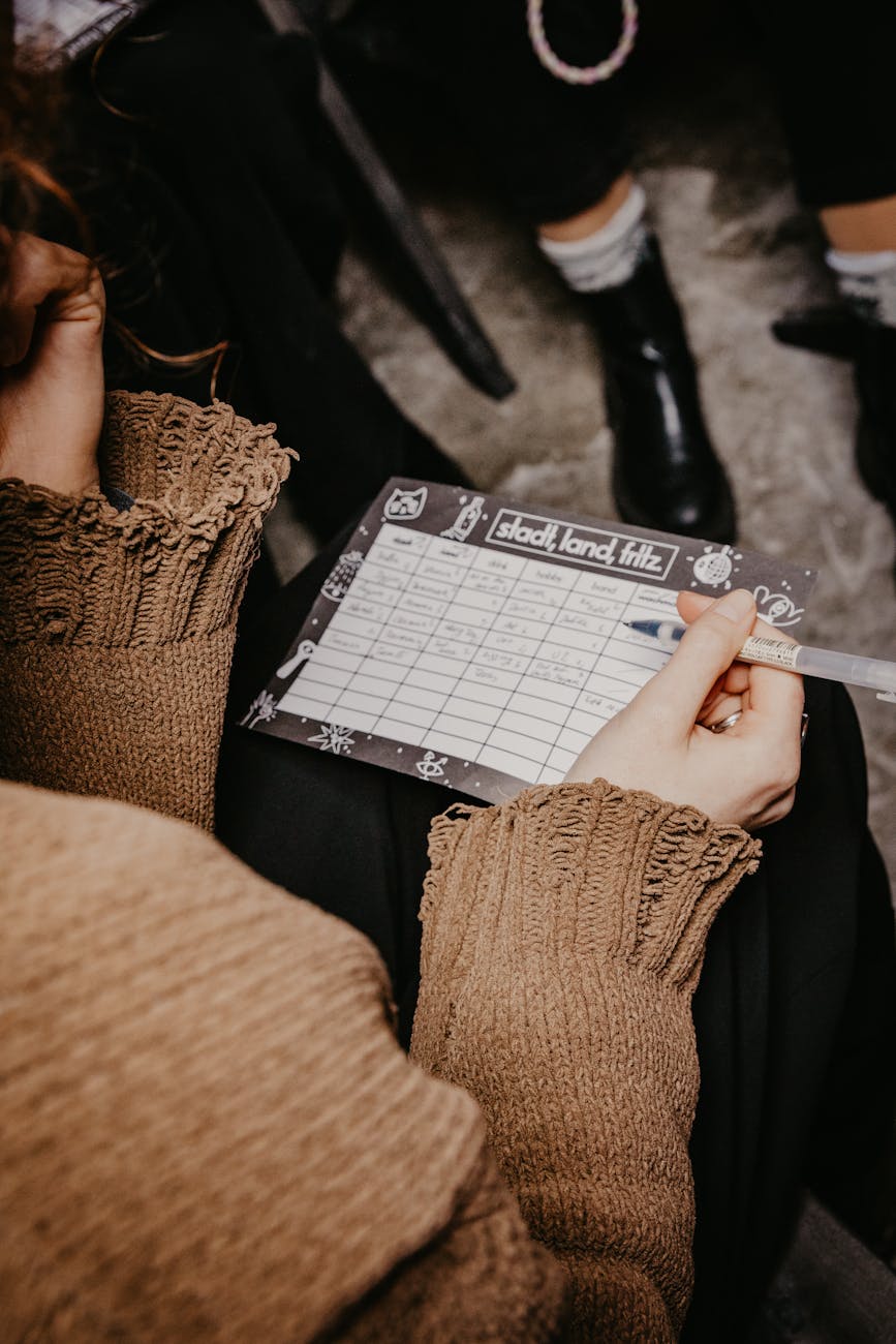 A woman writing on a paper playing a word game during a social gathering.