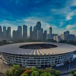 Stunning aerial view of Gelora Bung Karno Stadium with Jakarta skyline in the background.