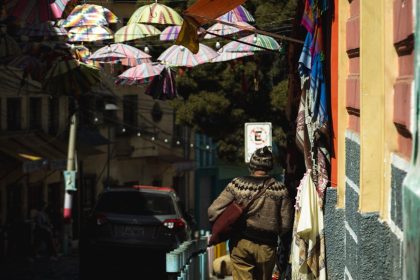Vibrant umbrellas hang above a city sidewalk, creating a colorful street decoration scene.