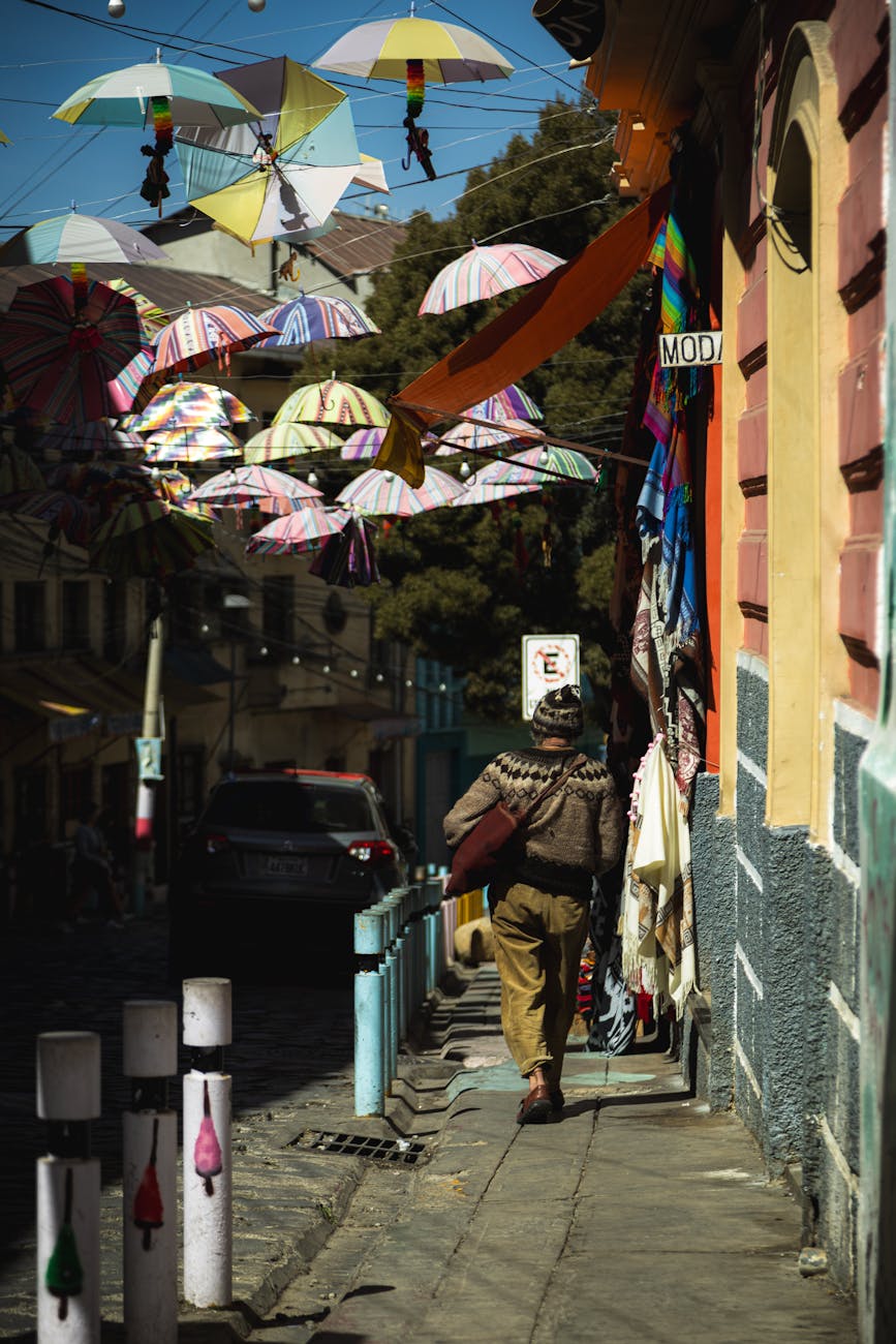 Vibrant umbrellas hang above a city sidewalk, creating a colorful street decoration scene.