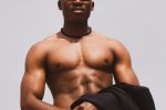 A strong, muscular black male wearing sunglasses, posing confidently outdoors in Lagos, Nigeria.