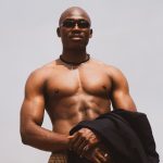 A strong, muscular black male wearing sunglasses, posing confidently outdoors in Lagos, Nigeria.