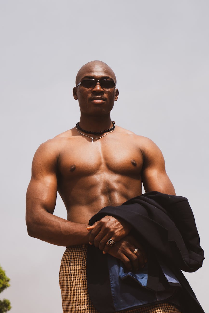 A strong, muscular black male wearing sunglasses, posing confidently outdoors in Lagos, Nigeria.
