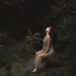 Young woman meditating in a tranquil forest setting, embracing nature's serenity.