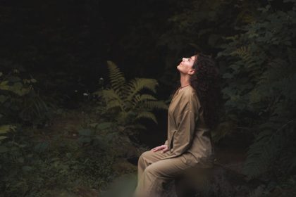 Young woman meditating in a tranquil forest setting, embracing nature's serenity.