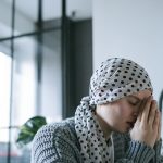 A woman wearing a polka dot scarf prays with hope, symbolizing strength and recovery during illness.