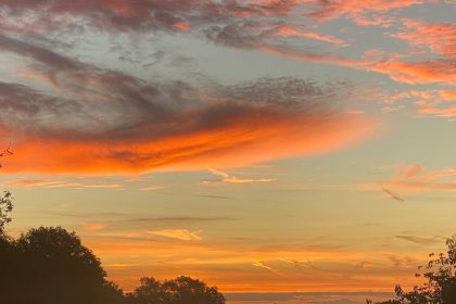 Vivid autumn sunrise with orange clouds over a misty golf course in Sheffield, UK.
