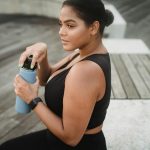 A woman in sportswear holding a water bottle outdoors, embracing a healthy lifestyle.