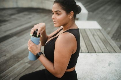 A woman in sportswear holding a water bottle outdoors, embracing a healthy lifestyle.
