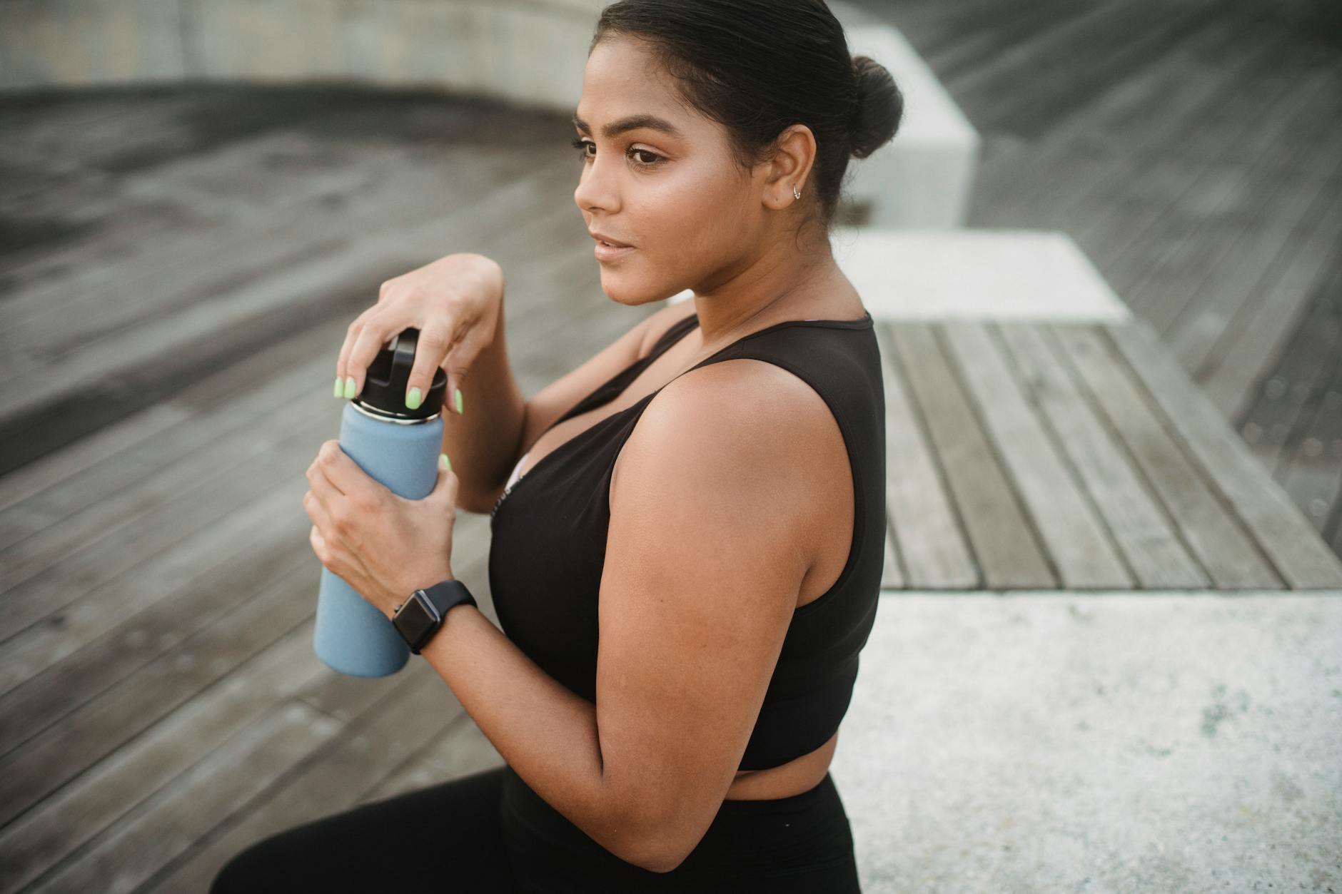 A woman in sportswear holding a water bottle outdoors, embracing a healthy lifestyle.