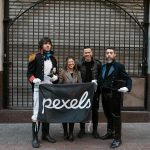 People posing with a Pexels banner in Buenos Aires, featuring historical costumes.