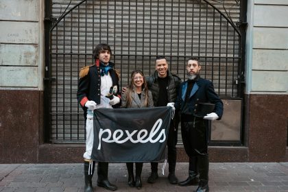 People posing with a Pexels banner in Buenos Aires, featuring historical costumes.