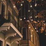 A picturesque European street illuminated with festive lights hanging from trees during nighttime.