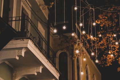 A picturesque European street illuminated with festive lights hanging from trees during nighttime.