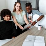 A diverse group of young professionals collaborate over documents in a modern office.
