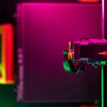 Close-up of a 3D printer in neon lights with futuristic vibe.